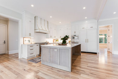 Large transitional l-shaped medium tone wood floor and beige floor open concept kitchen photo in Atlanta with an undermount sink, beaded inset cabinets, white cabinets, quartz countertops, white backsplash, subway tile backsplash, paneled appliances, an island and white countertops