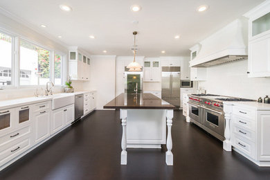 Inspiration for an expansive transitional u-shaped eat-in kitchen in Los Angeles with a farmhouse sink, raised-panel cabinets, white cabinets, quartz benchtops, white splashback, subway tile splashback, stainless steel appliances, dark hardwood floors, with island and brown floor.