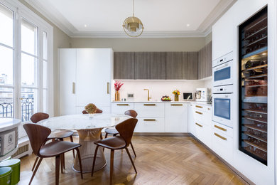 Design ideas for a contemporary l-shaped eat-in kitchen in Paris with flat-panel cabinets, white cabinets, white splashback, panelled appliances, medium hardwood floors and white benchtop.