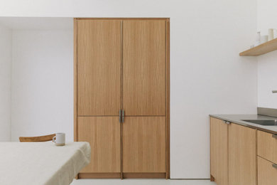 Modelo de cocina comedor contemporánea de tamaño medio con fregadero integrado, puertas de armario de madera oscura, encimera de acero inoxidable y suelo de cemento