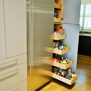 Réalisation d'une grande arrière-cuisine design en L avec un évier encastré, un placard à porte vitrée, des portes de placard en bois clair, une crédence blanche, une crédence en carreau de verre, un électroménager en acier inoxydable, un sol en bois clair et un îlot central.