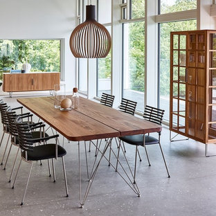 Réalisation d'une salle à manger design avec un mur blanc, aucune cheminée et béton au sol.
