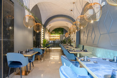 Immagine di una sala da pranzo aperta verso il soggiorno chic con pareti blu, pavimento con piastrelle in ceramica, pavimento grigio e soffitto a volta