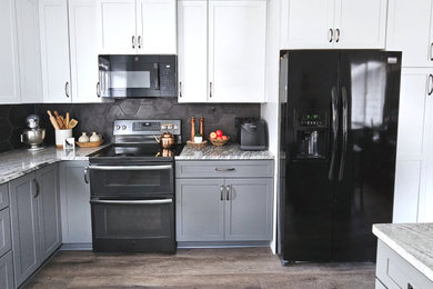 Trendy l-shaped laminate floor enclosed kitchen photo in Boise with an undermount sink, shaker cabinets, quartz countertops, black backsplash, mosaic tile backsplash and black appliances