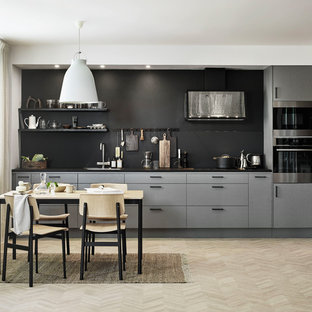 Idéer för att renovera ett skandinaviskt svart linjärt svart kök och matrum, med en undermonterad diskho, släta luckor, grå skåp, svart stänkskydd, integrerade vitvaror, ljust trägolv och beiget golv