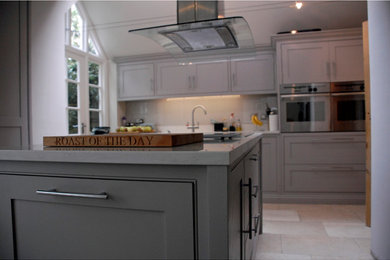Große Klassische Küche mit Kassettenfronten, grünen Schränken, Quarzwerkstein-Arbeitsplatte, Glasrückwand und Kücheninsel in London