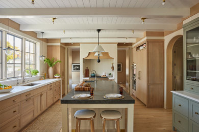 Design ideas for an expansive traditional u-shaped separate kitchen in New York with an undermount sink, shaker cabinets, beige cabinets, marble benchtops, beige splashback, timber splashback, panelled appliances, light hardwood floors, with island, beige floor, multi-coloured benchtop and timber.