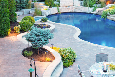 Transitional backyard custom-shaped lap pool in Toronto with natural stone pavers.