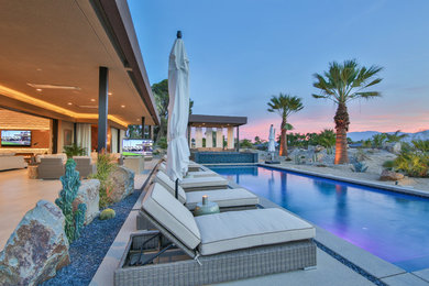 Example of a huge trendy backyard concrete patio design in Los Angeles with a roof extension and a fire pit