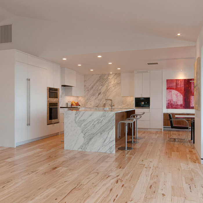 Example of a large trendy light wood floor, beige floor and vaulted ceiling eat-in kitchen design in Denver with an undermount sink, flat-panel cabinets, white cabinets, marble countertops, white back