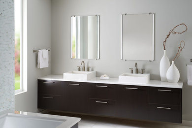 Inspiration for a large contemporary master bathroom in Montreal with flat-panel cabinets, dark wood cabinets, a corner tub, an open shower, a one-piece toilet, white tile, stone tile, grey walls, ceramic floors, a pedestal sink, solid surface benchtops, grey floor and an open shower.