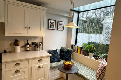 This is an example of a large galley enclosed kitchen in London with marble worktops, marble splashback, ceramic flooring, no island, beige floors and a feature wall.