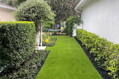 Photo of a small contemporary drought-tolerant and partial sun front yard mulch and vinyl fence garden path in Miami.