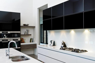 Large contemporary galley kitchen in Other with a double-bowl sink, white cabinets, quartz benchtops, white splashback, glass sheet splashback, black appliances, porcelain floors and with island.