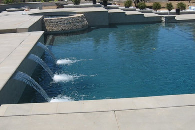 This is an example of a mid-sized modern backyard custom-shaped natural pool in San Diego with a hot tub and concrete slab.