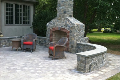 This is an example of a large country backyard patio in Wilmington with a fire feature, concrete pavers and no cover.