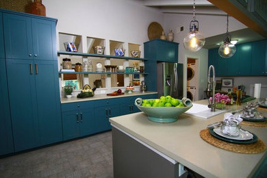 This is an example of a mid-sized transitional u-shaped eat-in kitchen in Atlanta with a farmhouse sink, shaker cabinets, blue cabinets, solid surface benchtops, stainless steel appliances, brick floors, with island, beige floor and beige benchtop.