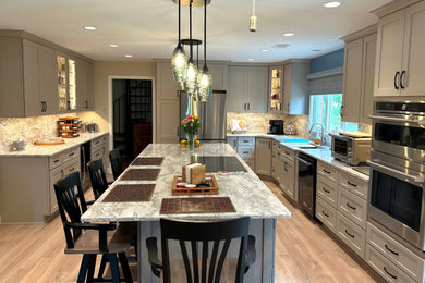 Example of a large u-shaped kitchen pantry design in DC Metro with an undermount sink, stainless steel appliances and an island