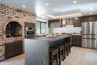 Eat-in kitchen - large industrial l-shaped eat-in kitchen idea in San Francisco with shaker cabinets, dark wood cabinets, quartz countertops, white backsplash, quartz backsplash, stainless steel appliances, an island, white countertops and an undermount sink