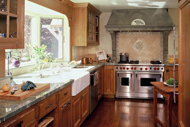 Example of a classic medium tone wood floor enclosed kitchen design in San Francisco with a farmhouse sink, recessed-panel cabinets, medium tone wood cabinets, marble countertops, beige backsplash, stone tile backsplash and stainless steel appliances