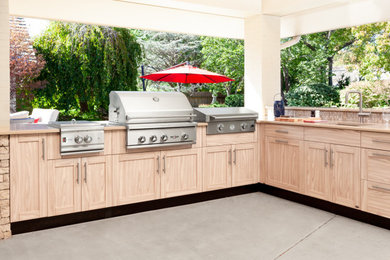 Cette image montre une grande terrasse arrière minimaliste avec une cuisine d'été, une extension de toiture et une dalle de béton.