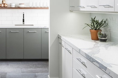 Inspiration for a mid-sized modern u-shaped kitchen in Grand Rapids with a single-bowl sink, flat-panel cabinets, white cabinets, quartzite benchtops, white splashback, subway tile splashback, stainless steel appliances and slate floors.