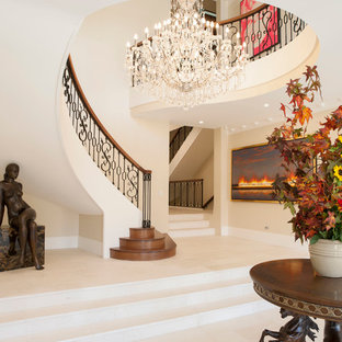 Пример оригинального дизайна интерьера: огромное фойе в классическом стиле с полом из известняка, двустворчатой входной дверью, входной дверью из дерева среднего тона и бежевыми стенами