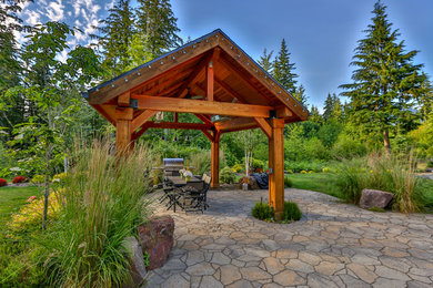 This is an example of a large arts and crafts backyard patio in Seattle with natural stone pavers and a gazebo/cabana.