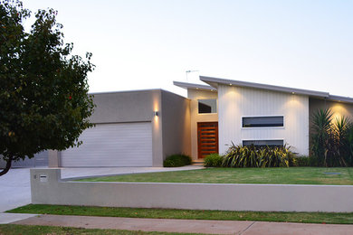 This is an example of a mid-sized contemporary one-storey beige exterior in Sydney with concrete fiberboard siding and a hip roof.