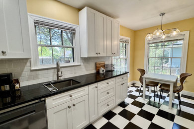 Small 1950s galley porcelain tile and multicolored floor eat-in kitchen photo in Austin with an undermount sink, shaker cabinets, white cabinets, quartz countertops, porcelain backsplash, stainless steel appliances, no island, white backsplash and black countertops