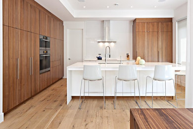 Inspiration for a mid-sized contemporary l-shaped light wood floor and beige floor open concept kitchen remodel in Calgary with flat-panel cabinets, medium tone wood cabinets, stainless steel appliances, an island and an undermount sink