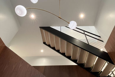Imagen de escalera minimalista sin contrahuella con escalones de madera, barandilla de metal y madera