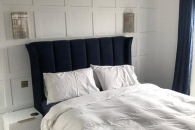 Large contemporary bedroom in Essex with white walls, vinyl flooring, grey floors, panelled walls and feature lighting.
