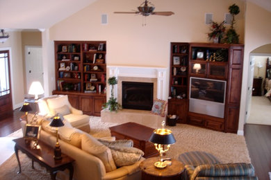 Ejemplo de salón para visitas tradicional de tamaño medio con paredes beige, suelo de madera oscura, marco de chimenea de madera, televisor retractable y suelo marrón