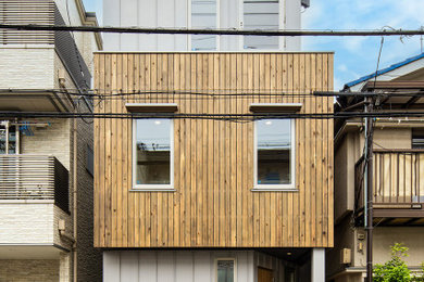 Cette image montre une façade de maison minimaliste en bois et planches et couvre-joints avec un toit en métal et un toit à deux pans.
