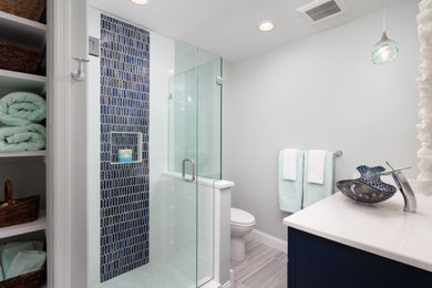 Foto på ett mellanstort eklektiskt vit badrum med dusch, med skåp i shakerstil, blå skåp, en hörndusch, en toalettstol med separat cisternkåpa, blå kakel, glaskakel, gröna väggar, klinkergolv i porslin, ett fristående handfat, bänkskiva i kvarts, flerfärgat golv och dusch med gångjärnsdörr
