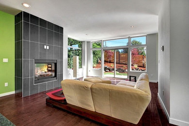 Photo of a mid-sized contemporary open concept living room in Seattle with multi-coloured walls, dark hardwood floors, a standard fireplace, a tile fireplace surround and no tv.