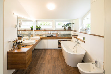 Modernes Badezimmer En Suite mit flächenbündigen Schrankfronten, hellbraunen Holzschränken, freistehender Badewanne, weißer Wandfarbe, dunklem Holzboden, Aufsatzwaschbecken, braunem Boden, brauner Waschtischplatte, Doppelwaschbecken, schwebendem Waschtisch und gewölbter Decke in Sonstige