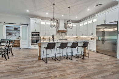Large transitional l-shaped porcelain tile and multicolored floor kitchen photo in Phoenix with a farmhouse sink, shaker cabinets, white cabinets, quartzite countertops, multicolored backsplash, porcelain backsplash, stainless steel appliances, an island and multicolored countertops