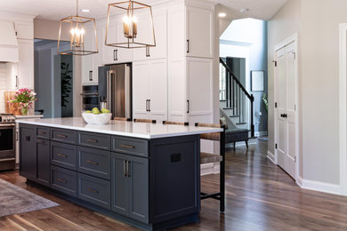 Design ideas for a large transitional u-shaped kitchen pantry in Cleveland with an undermount sink, shaker cabinets, grey cabinets, quartzite benchtops, white splashback, ceramic splashback, stainless steel appliances, light hardwood floors, with island, beige floor and white benchtop.