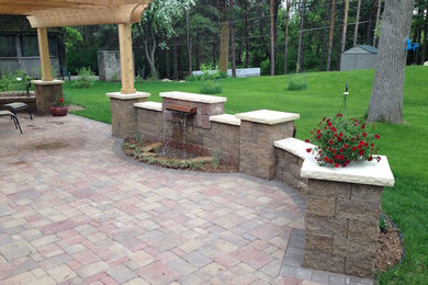 This is an example of a mid-sized traditional backyard patio in Minneapolis with a water feature, concrete pavers and a pergola.