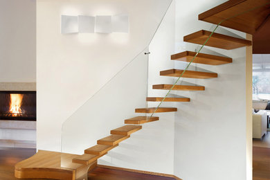 Photo of a mid-sized contemporary wood curved staircase in Paris with open risers and glass railing.
