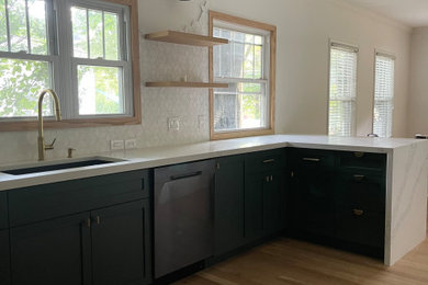 Mid-sized trendy galley light wood floor eat-in kitchen photo in Charlotte with an undermount sink, shaker cabinets, green cabinets, quartz countertops, white backsplash, ceramic backsplash, black appliances, an island and white countertops