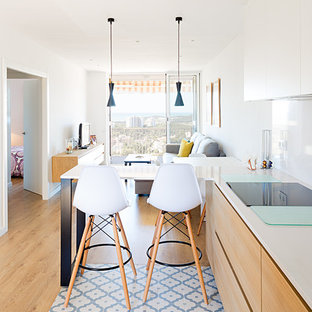 Kleines, Offenes Mediterranes Wohnzimmer ohne Kamin mit weißer Wandfarbe, hellem Holzboden, freistehendem TV und braunem Boden in Barcelona