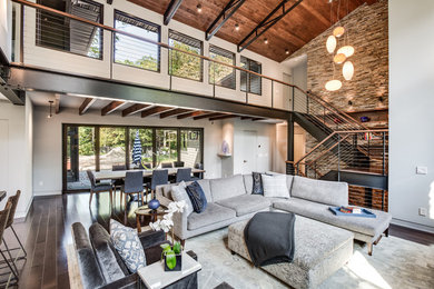 Large urban open concept dark wood floor and brown floor living room photo in Cleveland with white walls, a standard fireplace, a stone fireplace and a media wall
