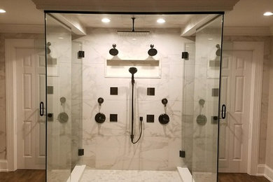 Example of a large transitional master black and white tile and porcelain tile medium tone wood floor and brown floor double shower design in Philadelphia with recessed-panel cabinets, white cabinets, a hot tub, a wall-mount toilet, gray walls, an undermount sink, quartz countertops, a hinged shower door and white countertops