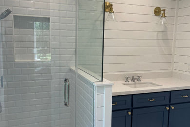 Inspiration for a coastal white floor, shiplap wall and ceramic tile corner shower remodel in Houston with blue cabinets, a hinged shower door, a niche, a built-in vanity and white walls