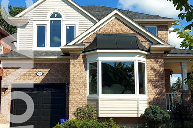 Example of a mid-sized classic two-story brick exterior home design in Toronto with a black roof