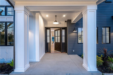 Ejemplo de entrada minimalista con paredes amarillas, suelo de cemento, puerta simple y puerta azul