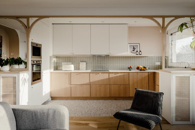 Cette photo montre une cuisine scandinave en L avec un placard à porte plane, des portes de placard blanches, un électroménager en acier inoxydable et un plan de travail blanc.
